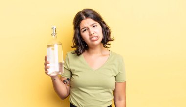 Genç İspanyol kadın şaşkın ve şaşkın hissediyor. su şişesi kavramı