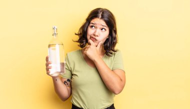 Genç İspanyol kadın düşünüyor, kuşkulu ve şaşkın hissediyor. su şişesi kavramı