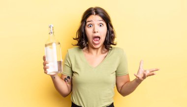 Genç İspanyol kadın şok olmuş ve şaşırmış hissediyor. su şişesi kavramı