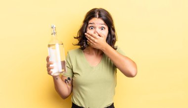 Genç İspanyol kadın şok olmuş ellerle ağzını kapatıyor. su şişesi kavramı
