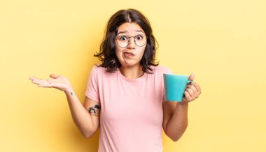 Genç İspanyol kadın şaşkın, şaşkın ve şüpheci hissediyor. kahve fincanı konsepti