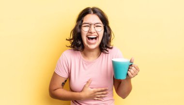 Genç İspanyol kadın komik bir şakaya yüksek sesle gülüyor. kahve fincanı konsepti