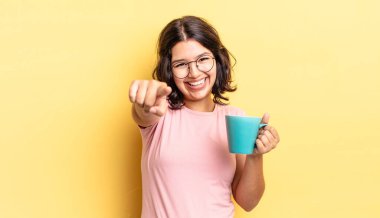 Genç İspanyol kadın kamerayı göstererek seni seçiyor. kahve fincanı konsepti