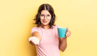 Genç İspanyol kadın mutlu bir şekilde gülümsüyor ve bir konsept sunuyor. kahve fincanı konsepti