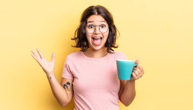 Genç İspanyol kadın kendini mutlu hissediyor ve inanılmaz bir şeye hayret ediyor. kahve fincanı konsepti
