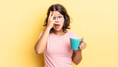 Genç İspanyol bir kadın şok olmuş, korkmuş ya da korkmuş görünüyor. Yüzü elle kapatılmış. kahve fincanı konsepti