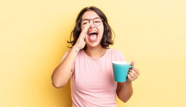 Genç İspanyol kadın kendini mutlu hissediyor, elleri ağzının kenarında bağırıyor. kahve fincanı konsepti