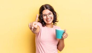 Genç İspanyol kadın gururla gülümsüyor ve kendinden emin bir numara oluyor. kahve fincanı konsepti