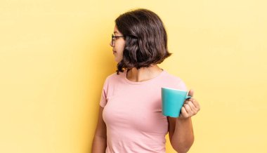 Profil görünümlü genç İspanyol kadın hayal mi kuruyor yoksa hayal mi kuruyor? kahve fincanı konsepti