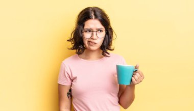 Genç İspanyol kadın üzgün, üzgün ya da kızgın hissediyor ve yana bakıyor. kahve fincanı konsepti