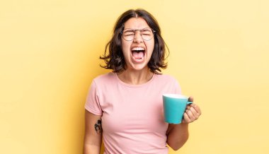 Genç İspanyol kadın agresif bir şekilde bağırıyor, çok kızgın görünüyor. kahve fincanı konsepti
