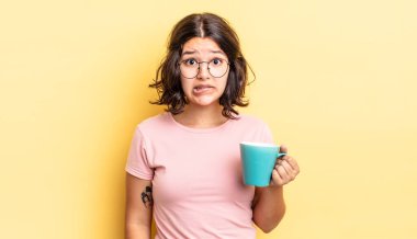 Genç İspanyol kadın şaşkın ve şaşkın görünüyor. kahve fincanı konsepti