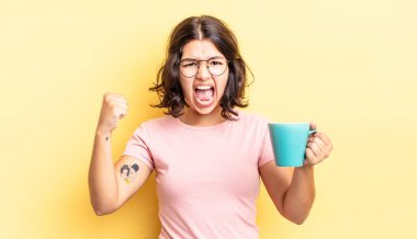 Genç İspanyol kadın öfkeli bir ifadeyle agresif bir şekilde bağırıyor. kahve fincanı konsepti