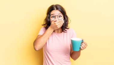 Genç İspanyol kadın şok olmuş ellerle ağzını kapatıyor. kahve fincanı konsepti