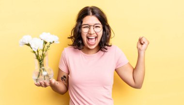 Genç İspanyol kadın şokta, gülüyor ve başarıyı kutluyor. çiçek saksı konsepti