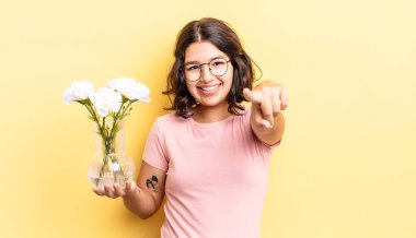 Genç İspanyol kadın kamerayı göstererek seni seçiyor. çiçek saksı konsepti