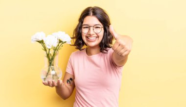 Genç İspanyol kadın gururlu, olumlu bir şekilde gülümsüyor. çiçek saksı konsepti