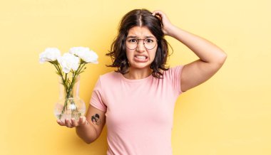 Genç İspanyol kadın stresli, endişeli ya da korkmuş hissediyor, elleri başının üstünde. çiçek saksı konsepti