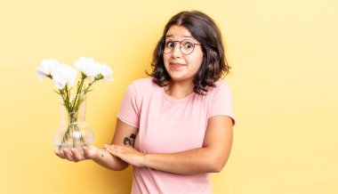 Genç İspanyol kadın omuz silkiyor, kafası karışık ve kararsız. çiçek saksı konsepti