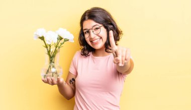 Genç İspanyol kadın gururla gülümsüyor ve kendinden emin bir numara oluyor. çiçek saksı konsepti