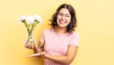 Genç İspanyol kadın neşeyle gülümsüyor, mutlu hissediyor ve bir konsept gösteriyor. çiçek saksı konsepti