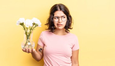 Genç İspanyol kadın üzgün, üzgün ya da kızgın hissediyor ve yana bakıyor. çiçek saksı konsepti