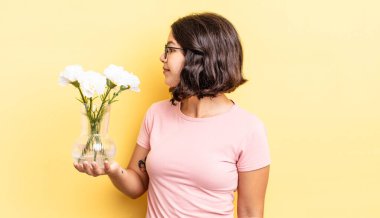 Profil görünümlü genç İspanyol kadın hayal mi kuruyor yoksa hayal mi kuruyor? çiçek saksı konsepti