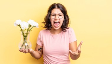 Genç İspanyol kadın kızgın, sinirli ve hayal kırıklığına uğramış görünüyor. çiçek saksı konsepti