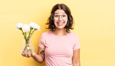 Genç İspanyol kadın mutlu ve hoş bir şekilde şaşırmış görünüyor. çiçek saksı konsepti