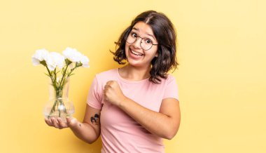 Genç İspanyol kadın kendini mutlu hissediyor ve bir meydan okumayla yüzleşiyor ya da kutluyor. çiçek saksı konsepti