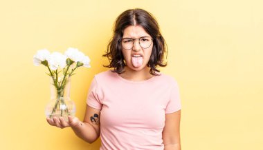 Genç İspanyol kadın iğreniyor, sinirleniyor ve dili dışarı çıkıyor. çiçek saksı konsepti