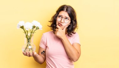 Genç İspanyol kadın düşünüyor, kuşkulu ve şaşkın hissediyor. çiçek saksı konsepti