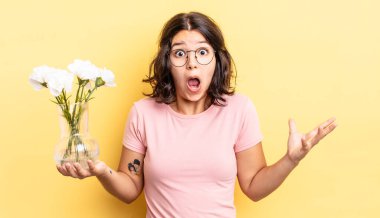 Genç İspanyol kadın şok olmuş ve şaşırmış hissediyor. çiçek saksı konsepti