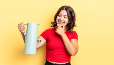 Genç İspanyol kadın mutlu ve kendinden emin bir ifadeyle gülümsüyor. Elleri çenesinde. termos kavramı