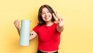 Genç İspanyol kadın gülümsüyor ve mutlu görünüyor, zafer ya da barış işareti yapıyor. termos kavramı