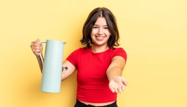 Genç İspanyol kadın mutlu bir şekilde gülümsüyor ve bir konsept sunuyor. termos kavramı