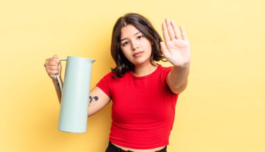 Genç İspanyol kadın ciddi görünüyor. Avuç içini gösteriyor. Durdurma hareketi yapıyor. termos kavramı