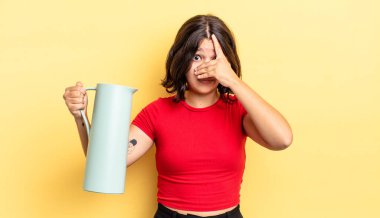 Genç İspanyol bir kadın şok olmuş, korkmuş ya da korkmuş görünüyor. Yüzü elle kapatılmış. termos kavramı