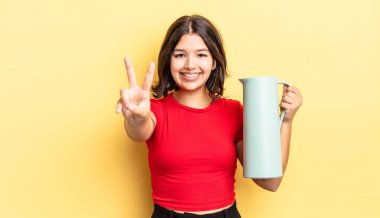 Genç İspanyol kadın gülümsüyor ve arkadaş canlısı görünüyor, iki numarayı gösteriyor. termos kavramı