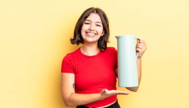 Genç İspanyol kadın neşeyle gülümsüyor, mutlu hissediyor ve bir konsept gösteriyor. termos kavramı