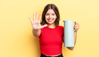 Genç İspanyol kadın gülümsüyor ve arkadaş canlısı görünüyor, beş numarayı gösteriyor. termos kavramı