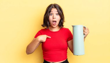 Genç İspanyol kadın şok olmuş ve ağzı açık, kendini işaret ederek şaşırmış görünüyor. termos kavramı