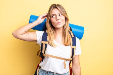 Güzel sarışın kız mutlu bir şekilde gülümsüyor ve hayal kuruyor ya da şüphe ediyor. Yürüyüş konsepti