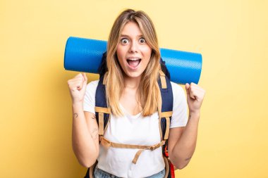 Güzel sarışın kız şokta, gülüyor ve başarıyı kutluyor. Yürüyüş konsepti