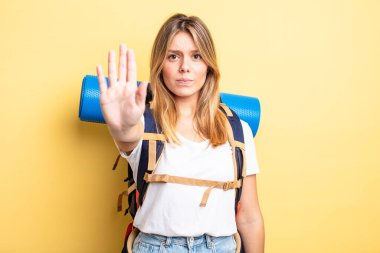 Güzel sarışın kız ciddi görünüyor. Avuç içini gösteriyor. Durma hareketi yapıyor. Yürüyüş konsepti