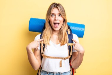 Güzel sarışın kız mutlu hissediyor ve heyecanla kendini işaret ediyor. Yürüyüş konsepti