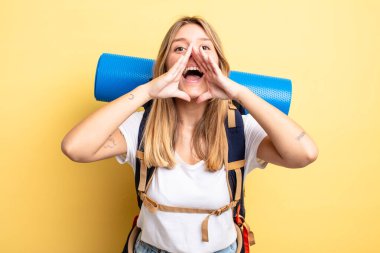 Güzel sarışın kız kendini mutlu hissediyor, elleri ağzının kenarında bağırıyor. Yürüyüş konsepti