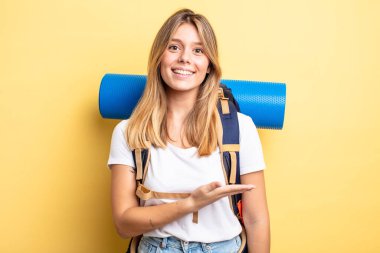 Güzel sarışın kız neşeyle gülümsüyor, mutlu hissediyor ve bir konsept gösteriyor. Yürüyüş konsepti