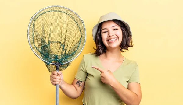 Genç İspanyol kadın neşeyle gülümsüyor, mutlu hissediyor ve bir tarafı işaret ediyor. balıkçı ağı kavramı