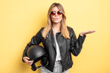 Güzel sarışın kız şaşkın, şaşkın ve şüpheci hissediyor. Motosiklet kaskı konsepti